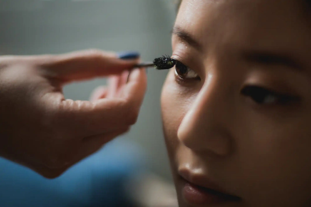 Someone applying mascara with a makeup brush.