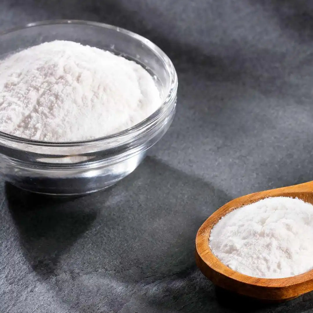 White powder in a glass bowl and wooden spoon.